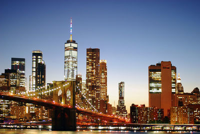 Illuminated buildings in city against clear sky