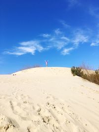 Sand dune on beach against blue sky