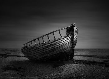 Abandoned boat on beach against sky