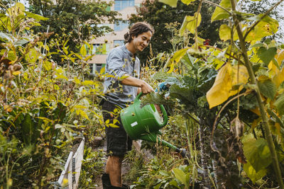 Smiling male volunteer watering plants in farm