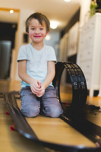 Portrait of boy sitting amidst toy racetrack