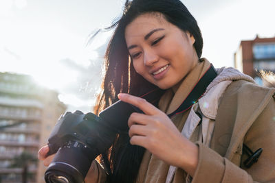 Portrait of smiling young woman holding camera during winter