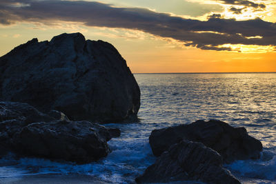 Rock formation on sea against sky during sunset