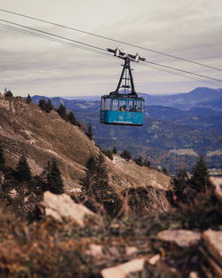 Overhead cable car over mountains against sky