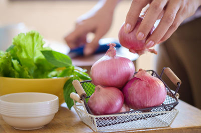 Cropped hands of woman chopping onions at table in kitchen