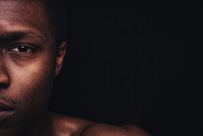 Close-up portrait of young man against black background