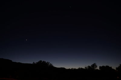 Low angle view of silhouette trees against sky at night