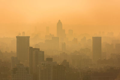 Modern buildings in city against sky during sunset