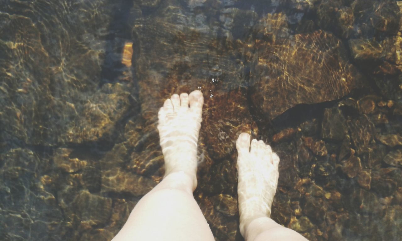 low section, person, personal perspective, lifestyles, human foot, standing, leisure activity, barefoot, shoe, water, high angle view, unrecognizable person, part of, sunlight, outdoors, day