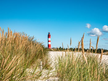 Lighthouse on beach against sky