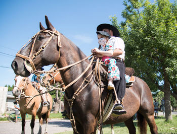 Argentinian father and daughter riding horse together