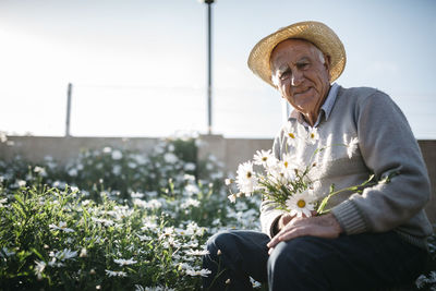 Portrait of senior man with picked flowers in his garden