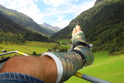 Midsection of man with arms outstretched against mountains