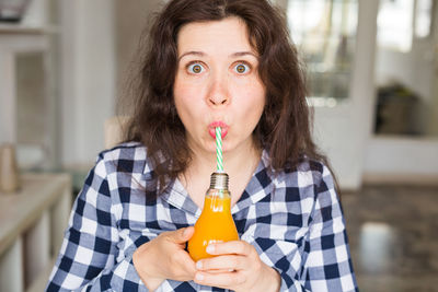 Portrait of smiling woman holding juice sitting at cafe