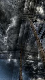 Low angle view of electricity pylon against cloudy sky