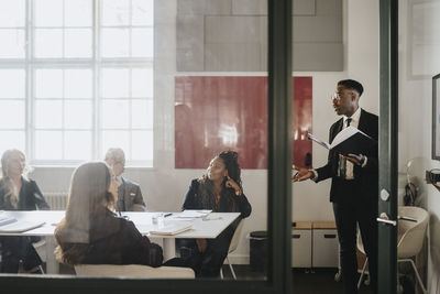 Mature businessman explaining male and female colleagues during meeting in board room at office