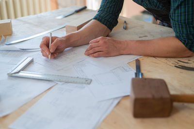 Midsection of architect working on blueprint in office