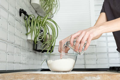Pouring water. making dough by female hands in kitchen in scandinavian stile. flour and water