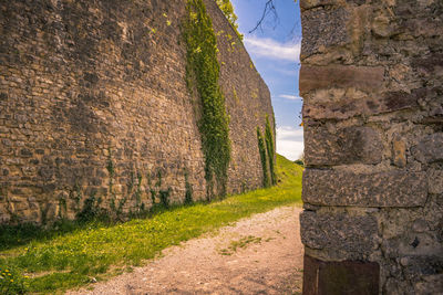 Footpath amidst stone wall against sky