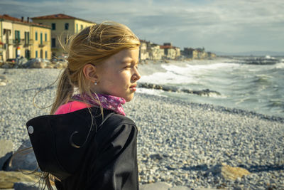 Girl standing at beach against sky