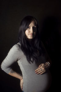 Portrait of woman standing against black background