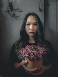 Portrait of a beautiful young woman standing against wall