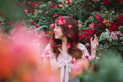 Portrait of young woman standing by plants