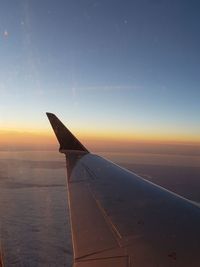 Airplane flying over sea against sky during sunset