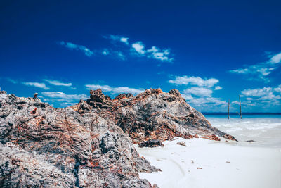 Rock formation on beach against blue sky
