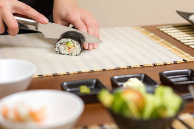 Midsection of person holding sushi on table