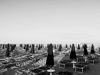 Chairs and table on beach against clear sky