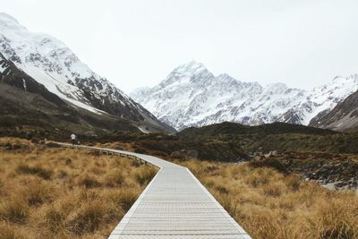 Boardwalk against snowcapped mountains