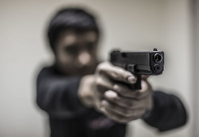 Man aiming with gun against wall