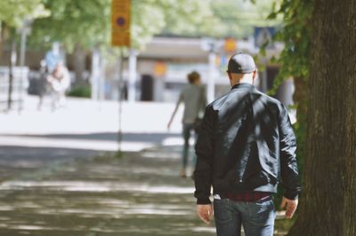 Rear view of man walking on footpath