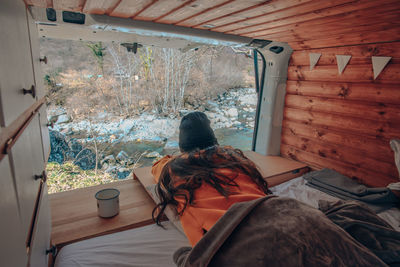 Rear view of woman sitting in snow