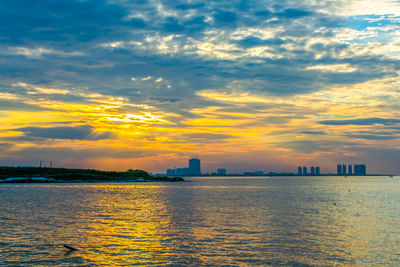 Scenic view of sea and buildings against sky during sunset