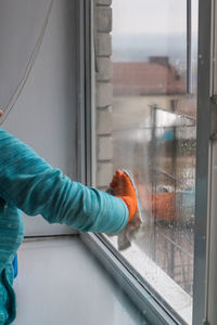 Midsection of woman looking through window