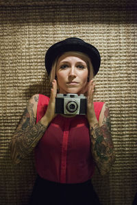 Portrait of woman wearing hat against wall