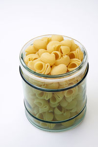 Close-up of pasta in jar over white background