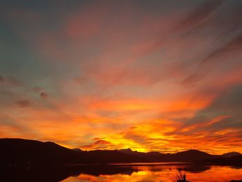 Scenic view of dramatic sky over silhouette mountains during sunset