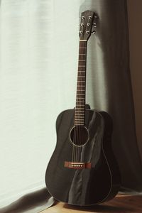 Close-up of guitar on table against wall at home