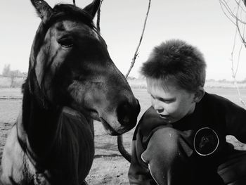 Cute boy with horse against clear sky