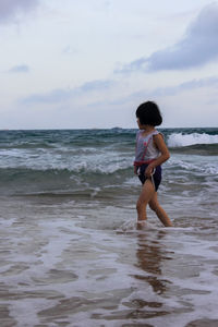 Full length of boy on beach against sky