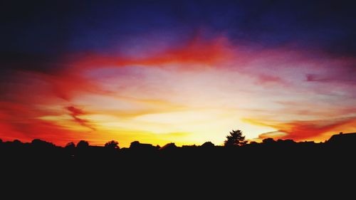 Silhouette landscape against dramatic sky during sunset