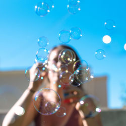 Woman blowing bubbles during sunny day