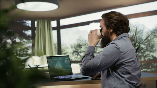 Young woman using laptop while sitting on table