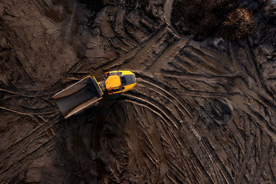 Aerial  dumper truck or earth mover on muddy soil and tyre tracks in construction industry on field