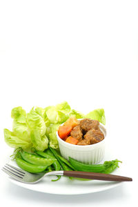 Close-up of food in plate against white background