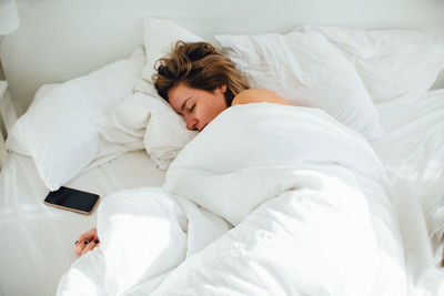 High angle view of young woman sleeping on bed