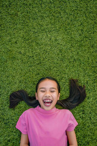Directly above shot of happy girl lying down on field